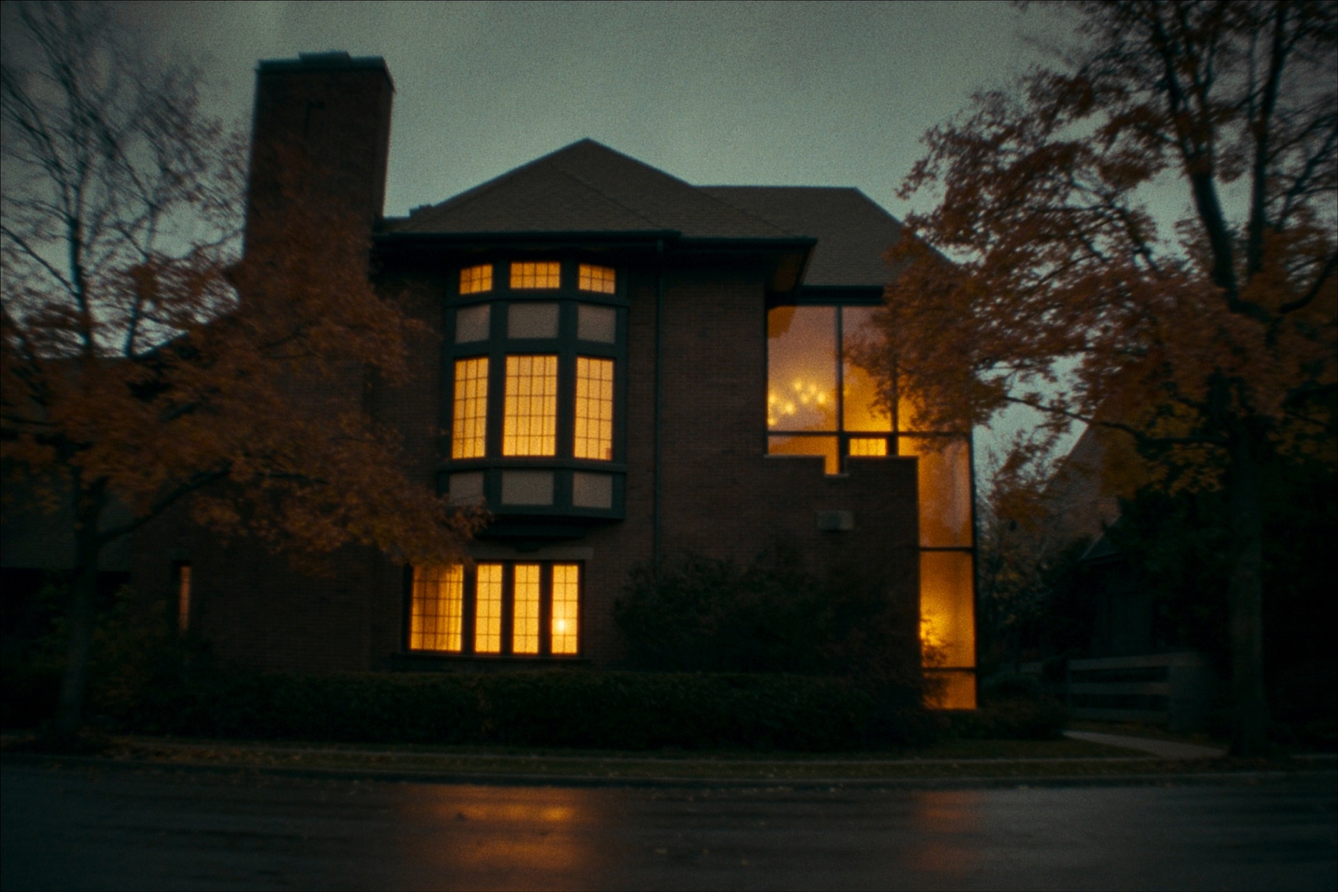 Kenwood — a rebuilt 1922 brick residence in Minneapolis at evening, warm lamplight behind tall street-facing windows